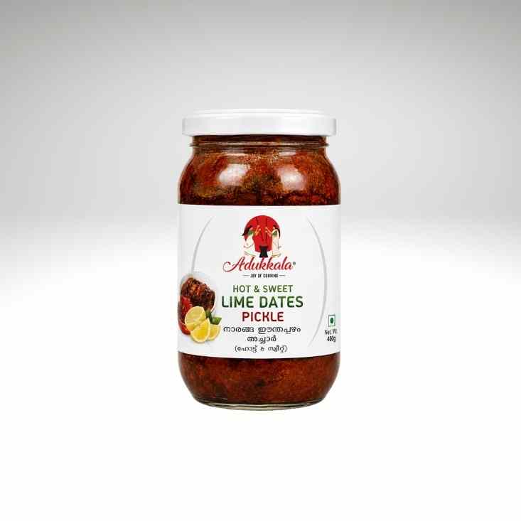 A jar of Adukkala Hot & Sweet Lime Dates Pickle on a light gray gradient background. The product is in a clear glass jar showing the dark red pickle contents, with a white label and a white screw cap.