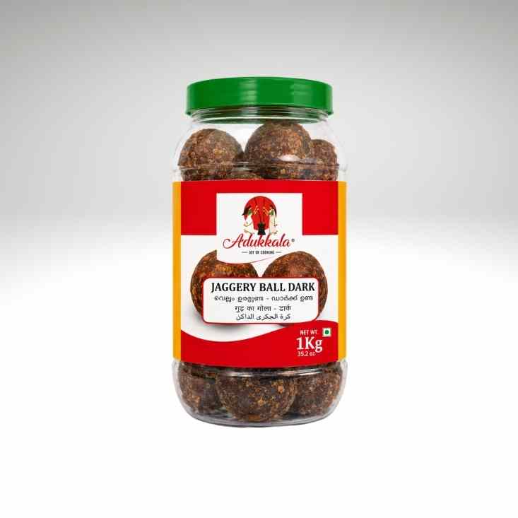 A 1 kg jar of Adukkala Jaggery Ball Dark, featuring dark brown jaggery balls inside a clear plastic jar with a green lid and a red and orange label.