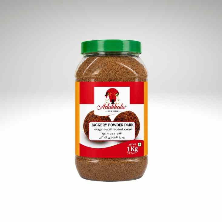 A 1 kg plastic jar of Adukkkala Jaggery Powder Dark with a green lid and a red and orange label, set against a light gray gradient background.