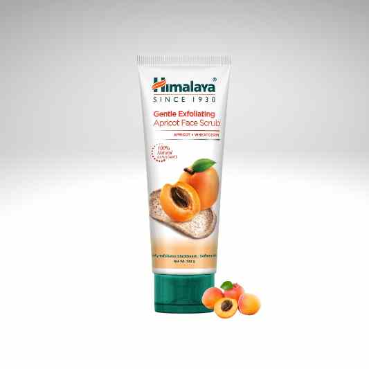 Himalaya Gentle Exfoliating Apricot Face Scrub in a white squeeze tube with a dark green cap, shown on a light gray gradient background with apricot illustrations and a few whole/apricot halves at the base.