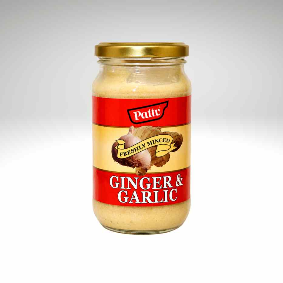 A glass jar of Pattu Freshly Mined Ginger & Garlic paste with a gold metal lid and a red and beige label, set against a light gray gradient background.