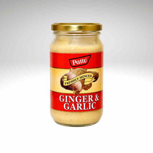 A glass jar of Pattu Freshly Mined Ginger & Garlic paste with a gold metal lid and a red and beige label, set against a light gray gradient background.